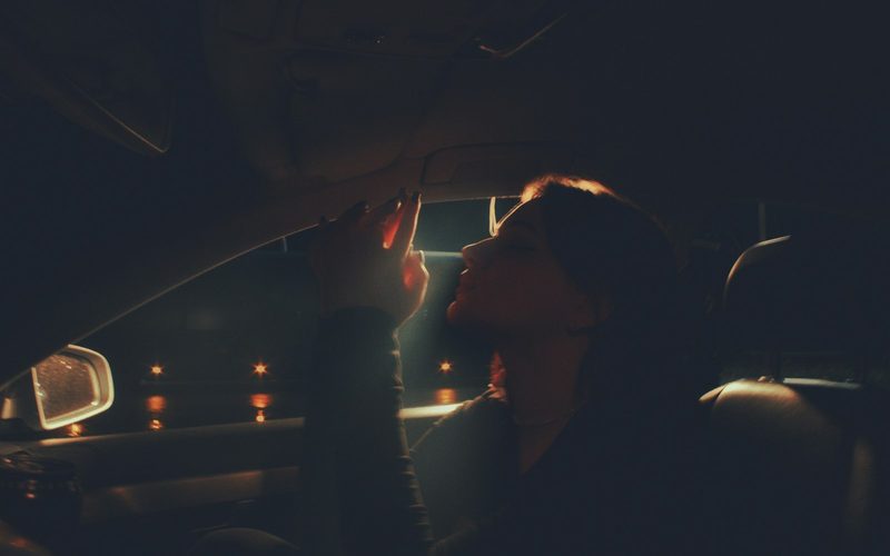 Passenger riding in a car at night with city lights outside the window